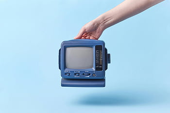 hand holding CRT TV, vintage blue television, light blue background, studio shot, retro TV, small CRT television, hand holding television, blue CRT TV, vintage television, studio photography, light blue backdrop