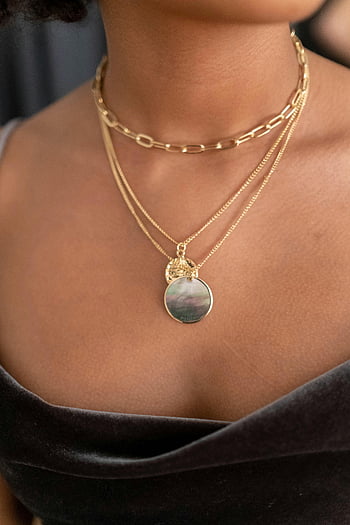 gold necklace, layered necklace, chic design, elegant jewelry, close-up photo, black top, skin texture, fashion accessory, gold chain, pendant necklace, woman wearing necklace