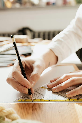 person writing, white paper, close-up, sketching, pencil, ruler, precision, artistry, hand, desk, drawing