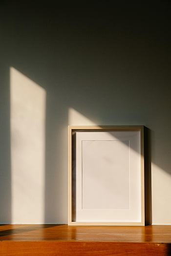 empty frame, wooden shelf, elegant minimalist frame, warm sunlight, interior decor, minimalist decor, empty picture frame, wooden surface, natural light, shadow play, home decor