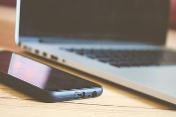 black Android smartphone, close-up view, smartphone, laptop, wooden desk, modern technology, technology illustration, desk setup, electronic devices, office gadgets, tech devices