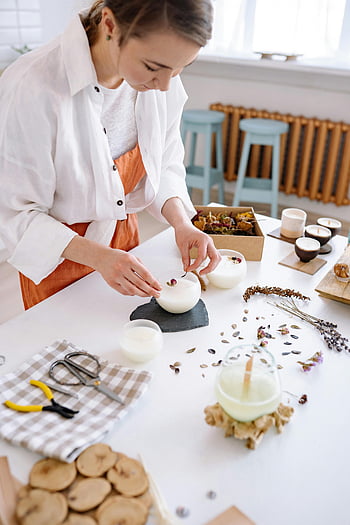 woman making candles, artisan candles, dried flowers, workshop setting, crafting candles, candle making, handmade candles, workshop table, candle workshop, candle crafting, dried flower candles