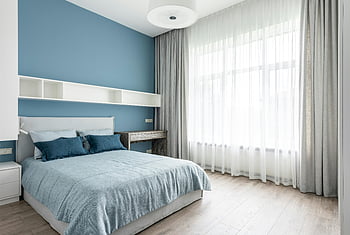 camera da letto contemporanea, letto morbido, cuscini blu, arredamento blu, luce naturale, grandi finestre, camera da letto serena, camera da letto moderna, biancheria da letto blu, pavimento di legno, tende bianche
