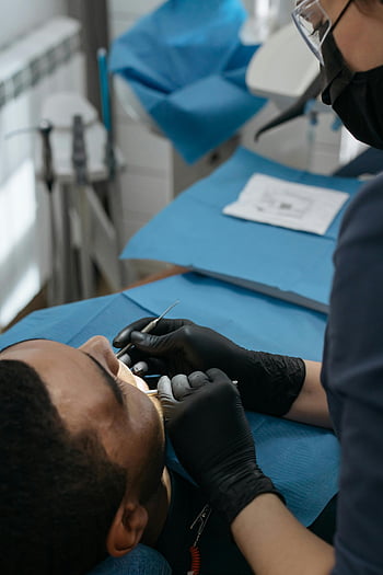 Zubní kontrola, zubař zkoumá pacienta, Rutinní dentální kontrola, zubní klinika, Zubní vyšetření, pacient na klinice, dentální nástroje, Zubní rukavice, zubní křeslo, dentální hygiena, Péče o zuby