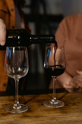personne versant du vin, vin rouge, verre de vin, table en bois, ambiance chaleureuse, bouteille de vin, action de coulée, dégustation de vins, salon, verrerie, boisson