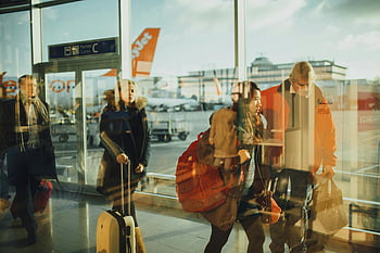 airport gate, passengers walking, glass walls, daytime travel, visible airplanes, airport terminal, people with luggage, airport passengers, airport interior, travel scene, airport gate area