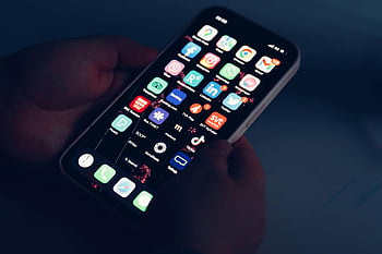 smartphone, touchscreen, app icons, close-up, hands holding, dimly lit room, mobile apps, smartphone display, app interface, smartphone apps, app icons close-up