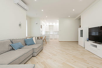 modern lägenhet, mjuk soffa, tv, rymligt vardagsrum, elegant möbler, ljus belysning, trägolv, samtida design, öppen layout, minimalistisk inredning, vit inredning