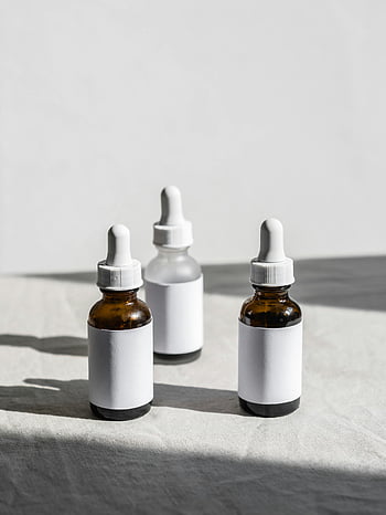 serumflaskor, droppar, tyg yta, naturligt ljus, närbild foto, hudvårdsprodukter, gula flaskor, vita etiketter, minimalisk inställning, skönhetsprodukter, kosmetiska flaskor