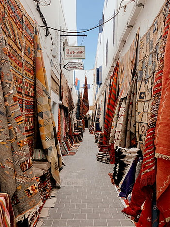 tappeti in mostra, vicolo vibrante, tappeti colorati, tappeti sospesi, luce naturale, Alley di mercato, Display tessile, mercato all'aperto, tappeti tradizionali, mercatino, mercato culturale