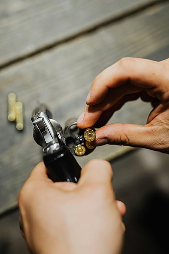 hands, revolver, bullets, wooden surface, detailed shot, loading, silver and black gun, close-up, firearm, ammunition, human hands
