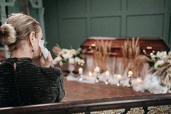 woman mourning, funeral, coffin, flowers, candles, church, grief, tears, memorial service, somber, remembrance
