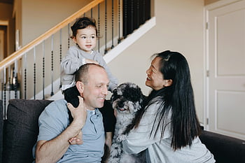 family, gray sofa, pet dog, multiethnic family, indoor bonding, love and togetherness, joyful family, family time, pet owner, living room, staircase background