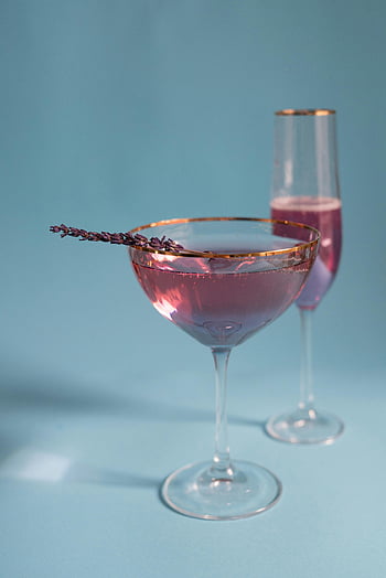 lavender-infused champagne, elegant glasses, soft blue backdrop, luxurious drinks, alcoholic beverages, cocktail glasses, purple champagne, elegant cocktails, champagne glasses, blue background, lavender garnish