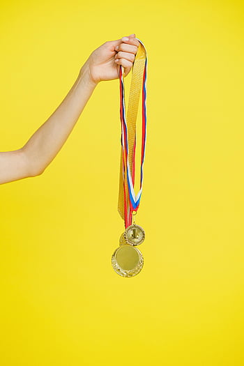 금메달, 손을 잡고 메달, 승리의 상징, 성취 상징, 생생한 노란색 배경, 근접 사진, 메달 리본, 승리하는 상징, 성공 기호, 노란색 배경