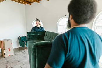 men carrying couch, green couch, sunlit room, packed boxes, movers, moving day, indoor moving, furniture moving, home moving, moving services, moving process