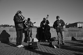 fotografie ve stupních šedi, lidé hrají nástroje, hudebníci vystupují, venkovní výkon, Monochromatické nastavení, pouliční muzikanti, živá hudba, venkovní koncert, Černý a bílý, hudební nástroje, veřejnosti
