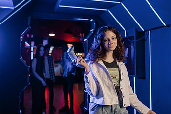 girl holding game controller, neon-lit arcade, young girl gaming, shallow focus photography, arcade environment, game controller, neon lights, immersive gaming, arcade atmosphere, gaming culture, arcade gaming
