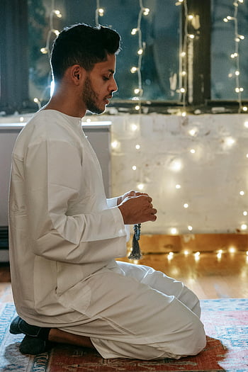 Muslim man, white thobe, praying, traditional clothing, indoor, string lights, side view, religious, spirituality, faith, prayer beads