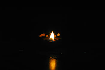 candle flame, yellow flame, close-up, illuminating darkness, serenity, warmth, candlelight, dark background, glowing light, peaceful ambiance, candle photography