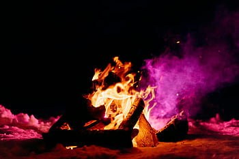 winter bonfire, snow, dark night sky, warm contrast, purple smoke, firewood, embers, outdoor gathering, wilderness camping, vibrant colors, cozy atmosphere