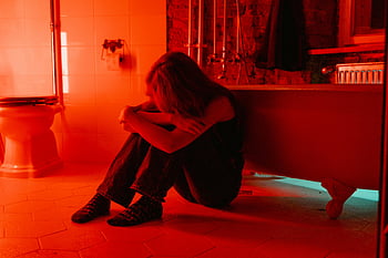 žena pláče, koupelna, červené osvětlení, osamělost, introspekce, emoční scéna, osamocená postava, emoční fotografie, Červená atmosféra, Nastavení koupelny, emocionální projev