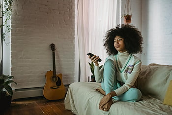 junge schwarze Dame, ruhen auf Sofa, Fernsehen, gemütliches Wohnzimmer, Lockige haare, Entspannen auf der Couch, Fernbedienung, Zuhause, junge Frau, Wohnzimmer, Sofa