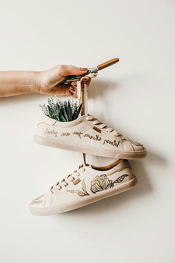 white sneakers, hand holding, decorated shoes, plant embroidery, creative quote, sneaker design, shoe art, unique footwear, fashion sneakers, eco-friendly shoes, sustainable fashion