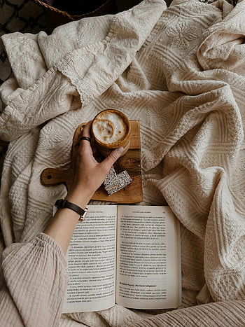 café, livre, moment de détente, couverture douce, main de femme, livre ouvert, atmosphère confortable, en train de lire, boisson chaude, temps libre, lecture réconfortante