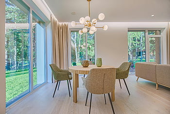 round brown wooden dining set, modern dining room, large windows, natural light, elegant furniture, contemporary dining table, dining chairs, indoor dining area, dining room decor, modern chandelier, natural wood flooring