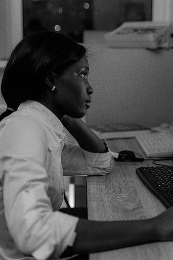black and white photo, woman using computer, grayscale image, computer desk, focusing on task, office work, professional setting, computer work, desk setup, work environment, black and white photography
