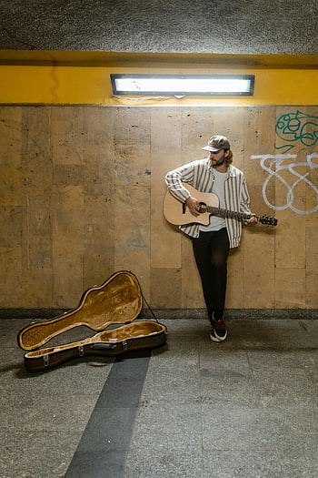 man playing guitar, brown acoustic guitar, urban subway, busking, graffiti wall, street musician, subway performer, guitar case, subway art, urban music, subway busker