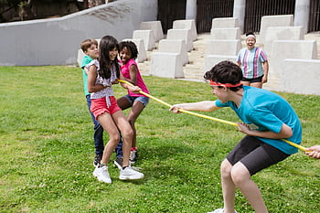 children playing tug of war, grass field, outdoor fun, park activities, cheerful children, active day, tug of war game, kids playing, outdoor games, park recreation, children's games