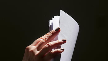 hand flipping pages, close-up hand, stack of papers, dark background, flipping through papers, close-up shot, document handling, paper stack, hand gesture, document review, document flipping