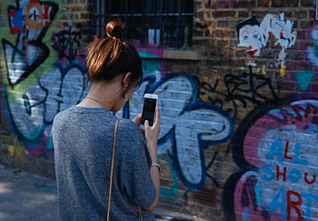 woman taking picture, mural wall, vibrant graffiti, urban setting, young woman, smartphone photography, street art, urban art, graffiti wall, cityscape, street photography
