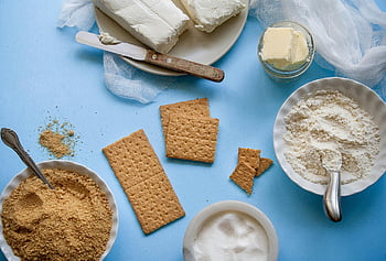 brown crackers, blue surface, flat lay, baking ingredients, butter, flour, graham crackers, blue background, sugar, cream cheese, knife