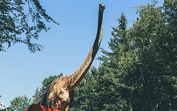 hnědý dinosaurus, socha dinosaura, venkovní park, zeleň, modrá obloha, velký dinosaurus, Prehistorické stvoření, přírodní scéna, venkovní socha, výstava dinosaurů, dinosaurus model