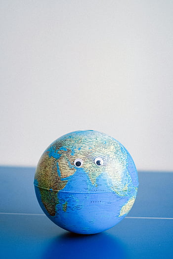globe, googly eyes, Earth miniature, global awareness, environmental consciousness, blue surface, sphere shaped, Earth model, planet representation, world map, eco-friendly symbol
