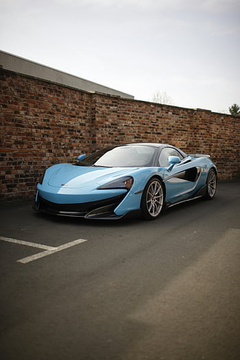 blaues Luxusauto, blauer Sportwagen, auf der Straße geparkt, rustikale Ziegelmauer, Pflaster, auffälliges blaues Auto, Luxusfahrzeug, Sportfahrzeug, Parkplätze im Freien, Autofotografie, städtischen Umfeld