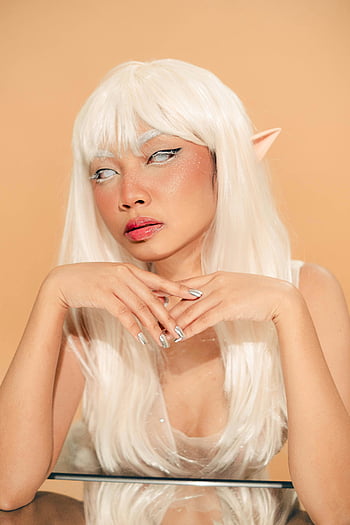 Pixie portrait, white hair, mirror table, studio portrait, eccentric woman, elf-like features, white wig, reflective surface, fantasy character, artistic photography, cosplay model