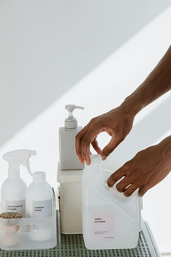 cleaning products, close-up view, hand opening, home care essentials, white surface, fabric softener, laundry liquid, multi-purpose cleaner, organizing products, cleanliness, hygiene