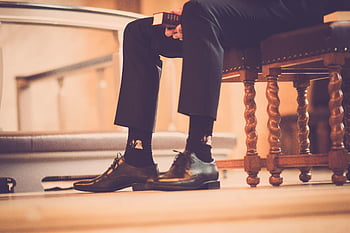 Elegante schoenen, sokken, serene kerk, reflectie, persoon zitten, holding boek, kerkelijke setting, Moment van reflectie, formele schoenen, kerk interieur, vreedzame scène