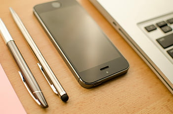 Space Gray iPhone 5s, retractable pens, MacBook, neatly arranged desk, smartphone, laptop, office setting, desk setup, tech gadgets, workspace, office tools