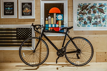 black bicycle, indoor parking, framed art, stylish look, modern design, black race bicycle, wooden wall, indoor decor, bicycle against wall, modern bicycle, indoor bicycle display