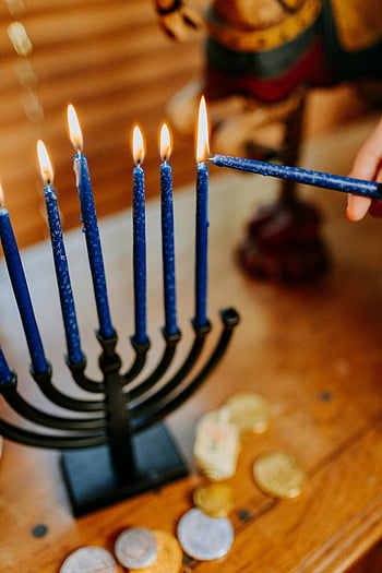 Chanukka, Menora, blaue Kerzen, Anzünden von Kerzen, Geltmünzen, jüdischer Feiertag, Festliche Szene, Traditionelle Feier, Winterfest, Kerzenlicht, Chanukka-Tradition