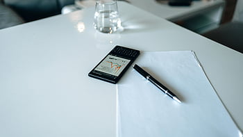 黒いスマートフォン、 画面上のグラフ、 洗練されたデスクのセットアップ、 グラフを表示するスマートフォン、 ペン、 紙、 机、 オフィス設定、 技術、 生産性、 ワークスペース