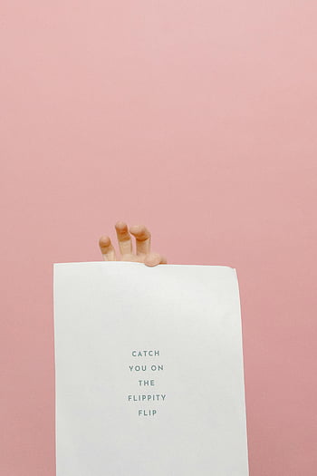 hand holding paper, Catch you on the flippity flip, pink background, playful design, minimalistic style, paper with phrase, hand gesture, fun quote, simple composition, pastel color, casual message