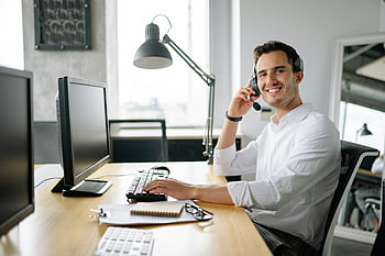 telefonos ügynök, fejhallgató, számítógép, modern iroda, mosolygás, asztal, fehér hosszú ujjú ing, dolgozó, irodai környezet, szakmai, technológia