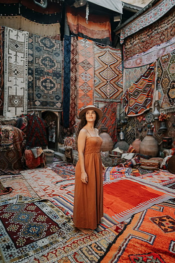 Turkish carpet market, Ürgüp, Türkiye, vibrant indoor market, woman exploring, traditional rugs, colorful carpets, cultural shopping, handmade textiles, travel destination, Middle Eastern decor