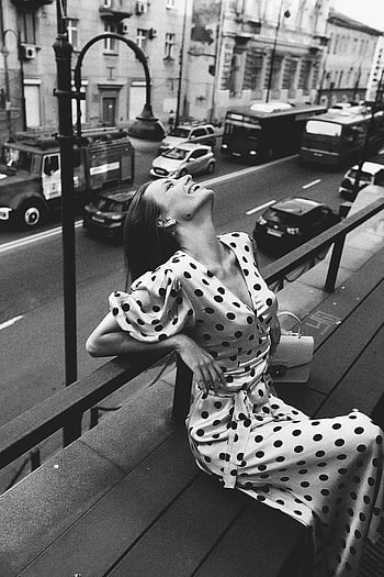 Schwarzweiss-Foto, Frau, Polka Dots Kleid, Stadtstraße, Bank, froh, einfarbig, städtische Szene, Mode, Strassenfotografie, Vintage-Stil